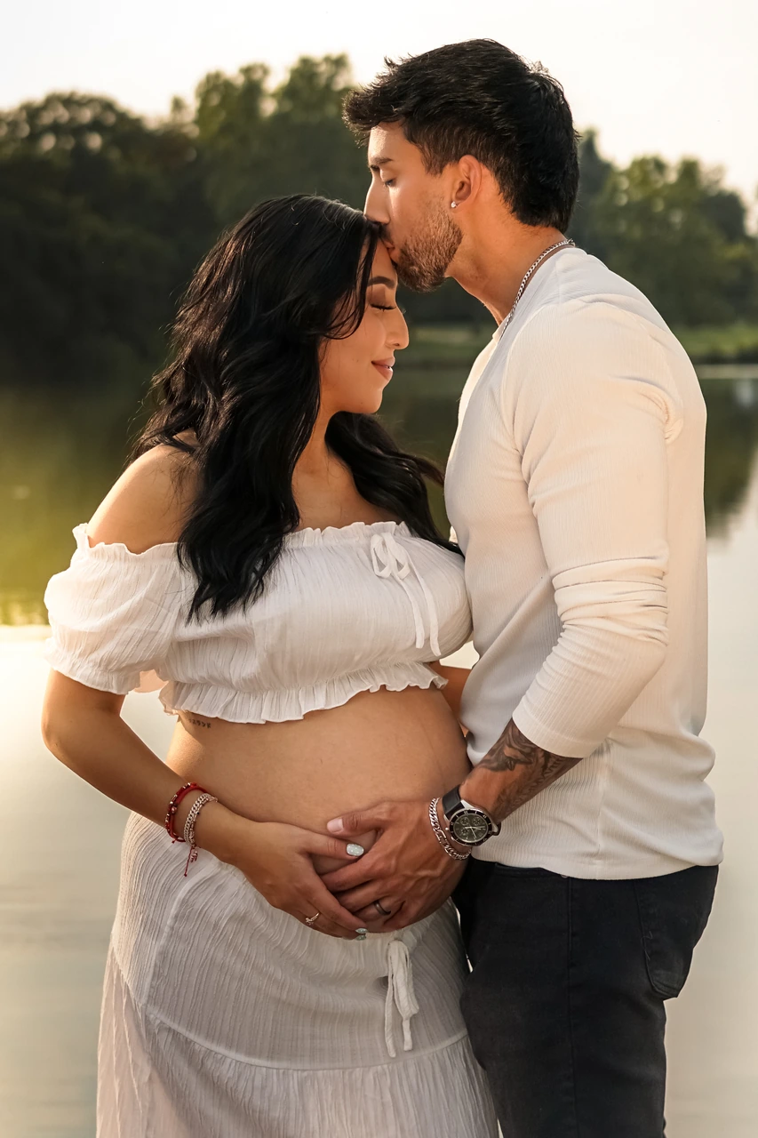 Man kissing his partner’s forehead beside the lake at golden hour