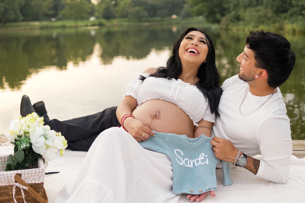 Expectant mother laughing with her partner while holding a blue Santi sweater