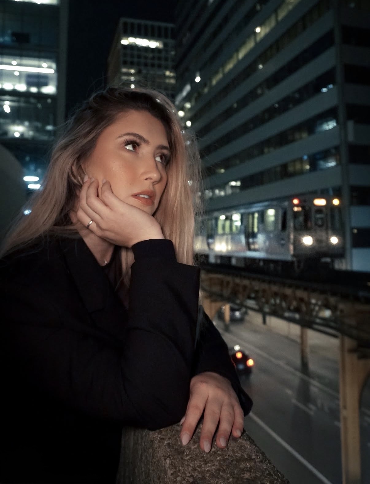 Woman beside city train tracks at night