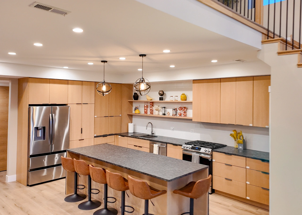 Modern kitchen with wood cabinets, stainless steel appliances and a large island beneath pendant lights