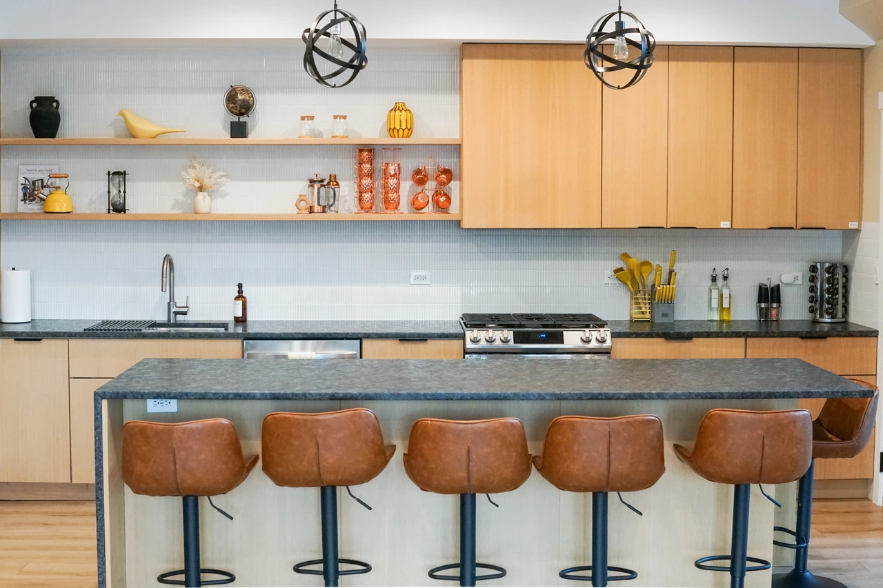 Front-facing kitchen composition with open shelves, pendant lights and leather island stools